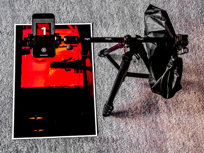 Zu sehen ist ein Smartphone in einem Stativ, dass ein Bild abfotografiert. 